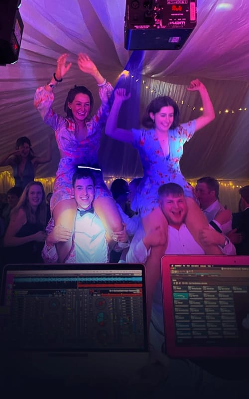 Two girls on boys shoulders at a party