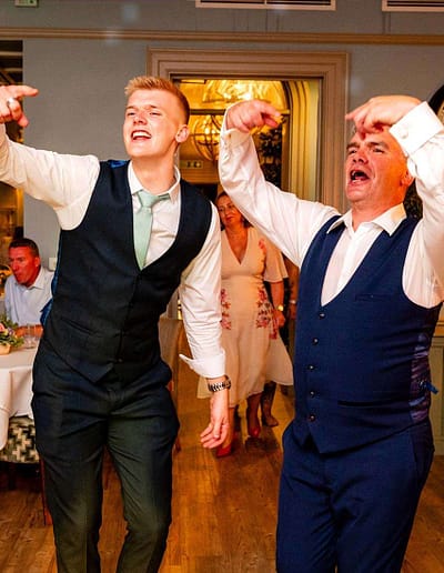 Two men dancing and singing at a wedding